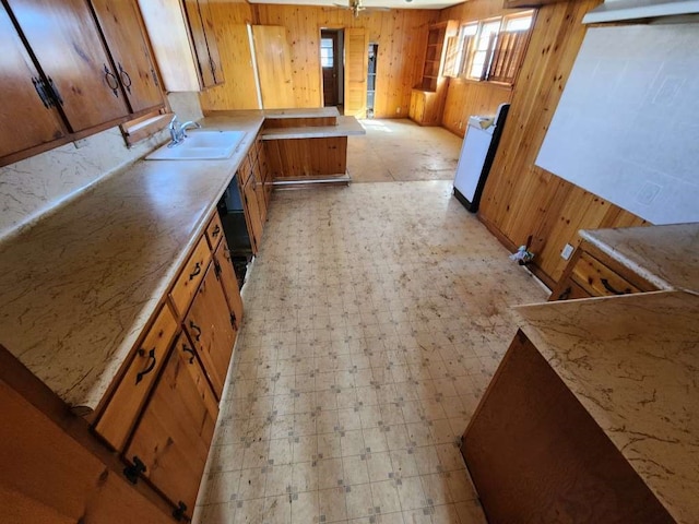 kitchen with wooden walls, sink, and light tile floors