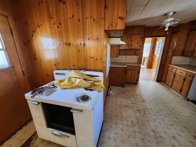 kitchen featuring ceiling fan, a healthy amount of sunlight, wood walls, and light tile floors