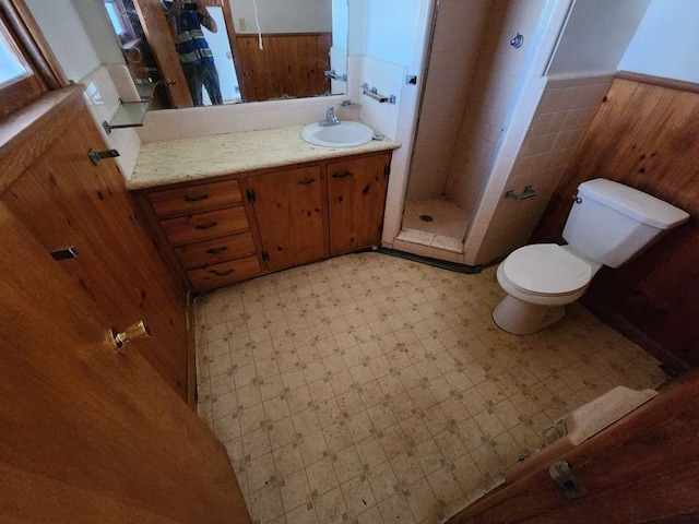 bathroom featuring tiled shower, tile flooring, vanity, and toilet