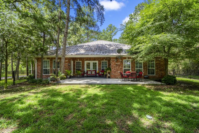 rear view of property featuring a lawn, french doors, and a patio