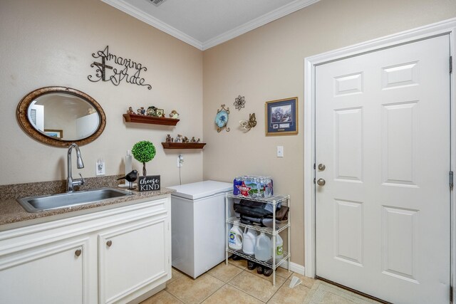 laundry area featuring sink, light tile patterned floors, and ornamental molding