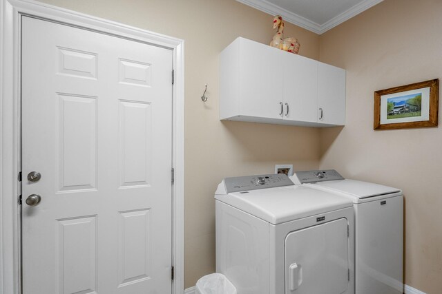 clothes washing area featuring cabinets, crown molding, and washing machine and clothes dryer