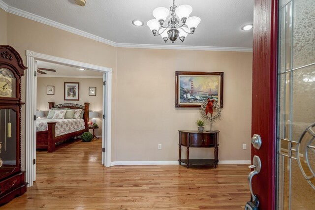 foyer entrance featuring light hardwood / wood-style flooring, an inviting chandelier, and ornamental molding