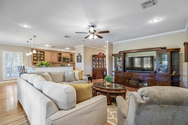 living room with light wood-type flooring, ceiling fan, and crown molding