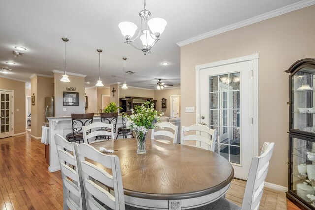 dining room featuring ceiling fan with notable chandelier, light hardwood / wood-style flooring, and crown molding