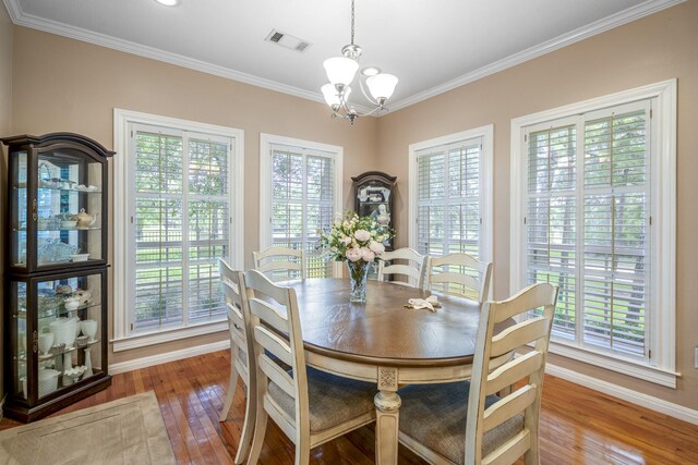 dining space with light hardwood / wood-style flooring, ornamental molding, plenty of natural light, and an inviting chandelier