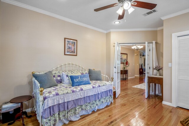 bedroom with ceiling fan with notable chandelier, wood-type flooring, and ornamental molding