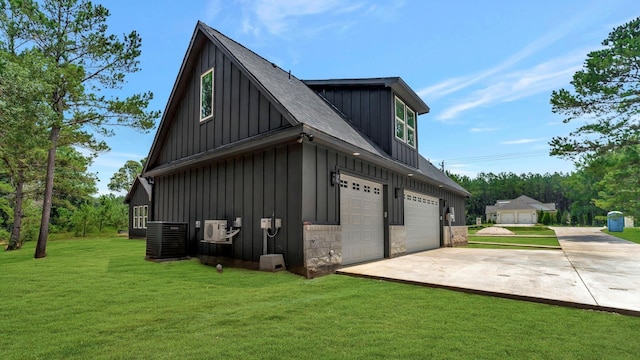 view of side of property featuring a yard, central AC unit, and a garage