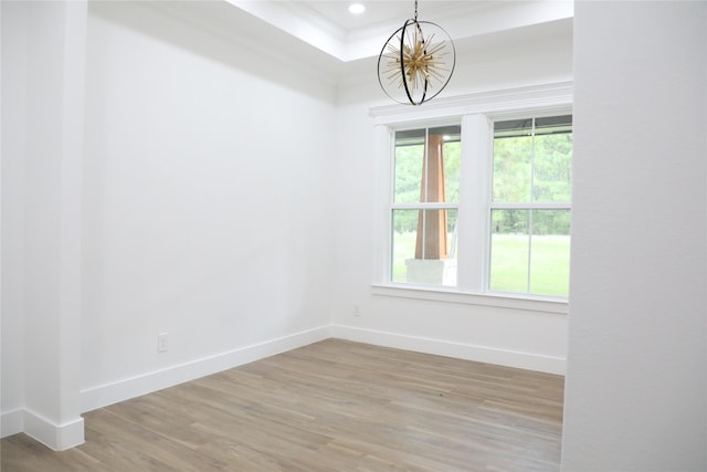 spare room featuring hardwood / wood-style flooring, a notable chandelier, and a raised ceiling