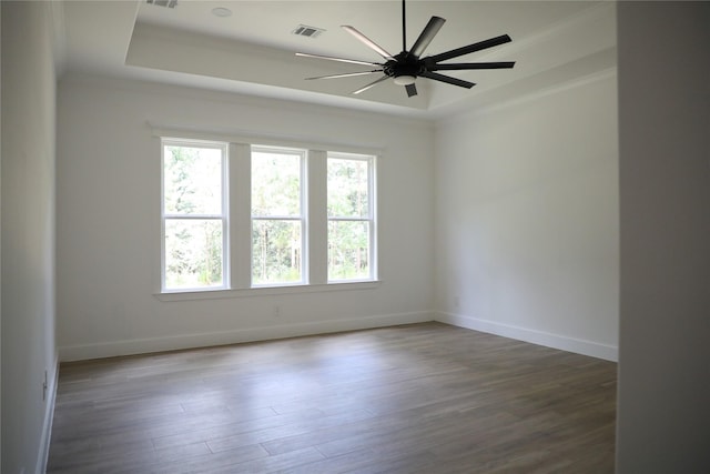 spare room featuring a raised ceiling, ceiling fan, dark hardwood / wood-style flooring, and ornamental molding