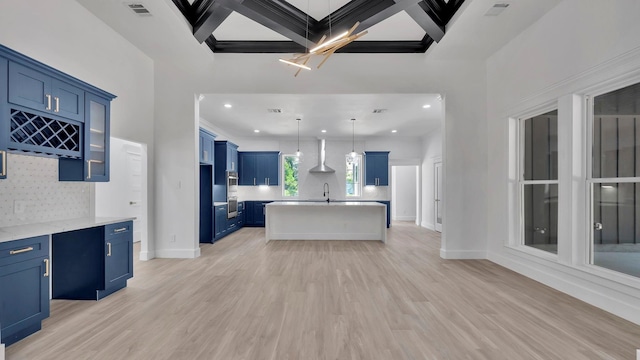 kitchen with wall chimney exhaust hood, coffered ceiling, beam ceiling, pendant lighting, and light hardwood / wood-style flooring