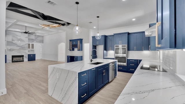 kitchen featuring light stone countertops, tasteful backsplash, stainless steel appliances, sink, and a center island with sink