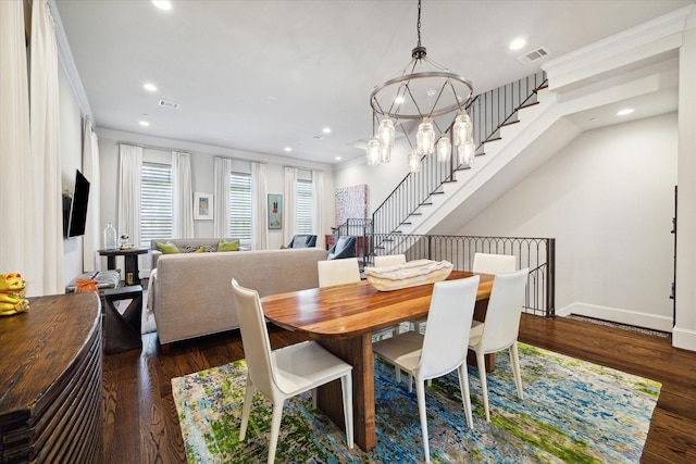 dining room featuring dark wood-type flooring, ornamental molding, and a notable chandelier