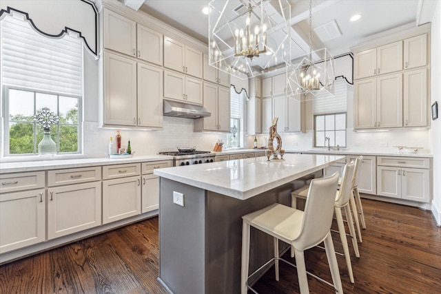 kitchen featuring a kitchen bar, dark wood-type flooring, a kitchen island, pendant lighting, and sink