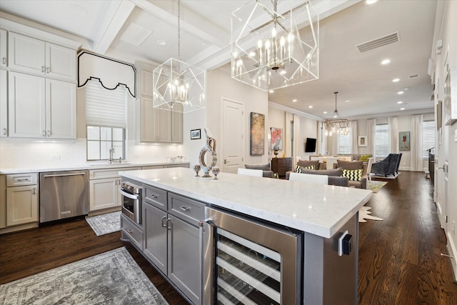 kitchen with white cabinets, beverage cooler, a center island, appliances with stainless steel finishes, and hanging light fixtures