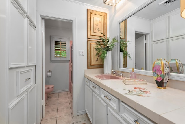 bathroom with tile floors, crown molding, toilet, and vanity with extensive cabinet space