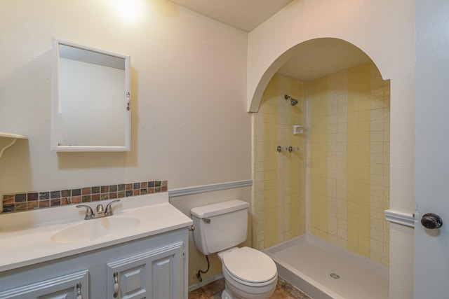 bathroom with vanity, toilet, and a tile shower