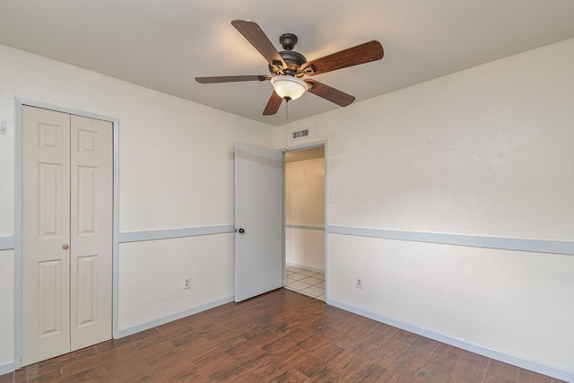 unfurnished bedroom with a closet, dark hardwood / wood-style floors, and ceiling fan