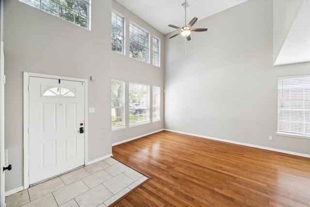 tiled foyer with ceiling fan and a towering ceiling