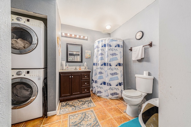 bathroom with tile flooring, stacked washer and dryer, vanity, and toilet