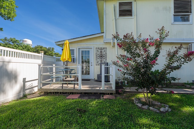 doorway to property featuring a deck and a lawn