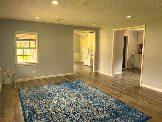 unfurnished room with a textured ceiling and dark hardwood / wood-style floors