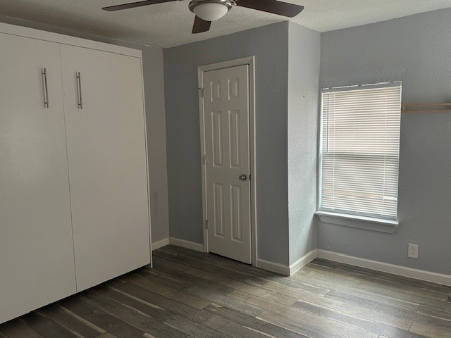 unfurnished bedroom with dark wood-type flooring, ceiling fan, and a textured ceiling