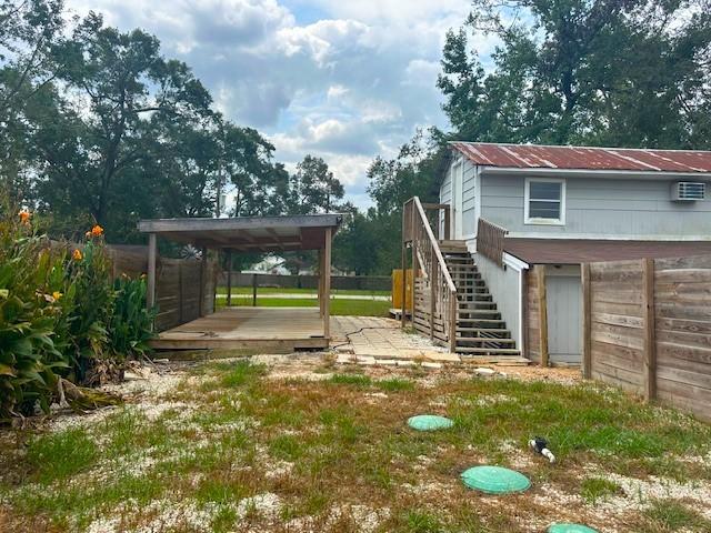 view of yard featuring a carport, a wall unit AC, a deck, and stairs