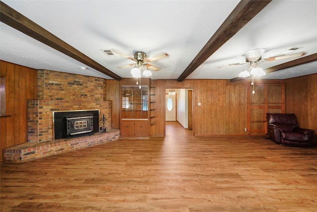 living room featuring beamed ceiling, ceiling fan, wooden walls, and light hardwood / wood-style floors