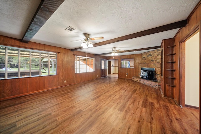 unfurnished living room featuring wood-type flooring, beam ceiling, and a textured ceiling