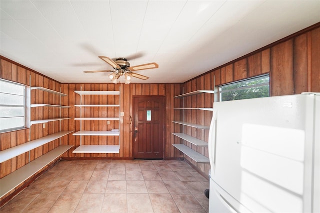 interior space with a wealth of natural light, wooden walls, and ceiling fan