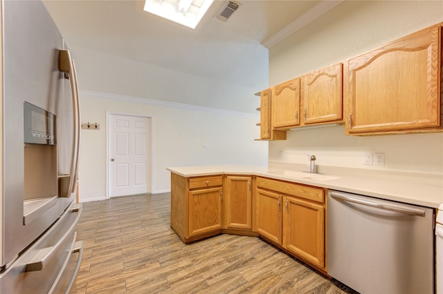 kitchen with sink, light wood-type flooring, ornamental molding, appliances with stainless steel finishes, and kitchen peninsula