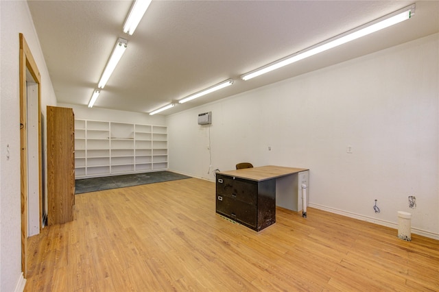 basement with a wall mounted AC and light hardwood / wood-style flooring