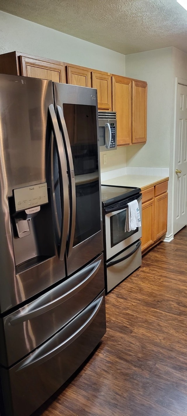 kitchen with appliances with stainless steel finishes, dark hardwood / wood-style floors, and a textured ceiling