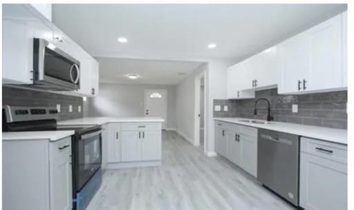 kitchen featuring light hardwood / wood-style floors, appliances with stainless steel finishes, white cabinets, backsplash, and sink