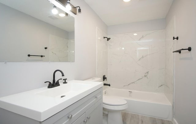 full bathroom with tiled shower / bath combo, vanity with extensive cabinet space, toilet, and hardwood / wood-style floors