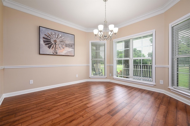 spare room featuring ornamental molding, hardwood / wood-style flooring, and a notable chandelier