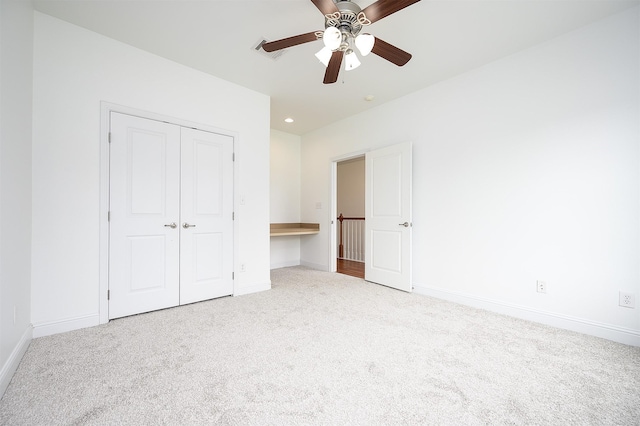 unfurnished bedroom featuring ceiling fan, a closet, and light colored carpet