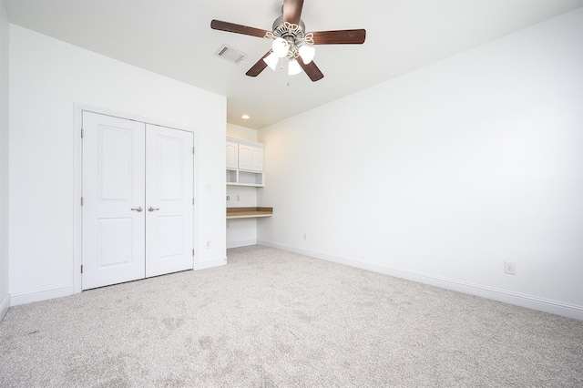 unfurnished bedroom with light carpet, a closet, and ceiling fan