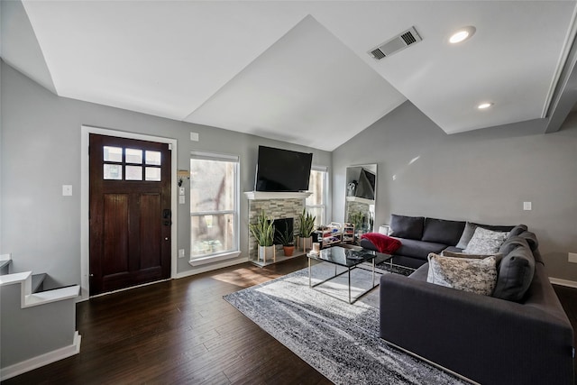 living room with a fireplace, a healthy amount of sunlight, lofted ceiling, and dark hardwood / wood-style flooring