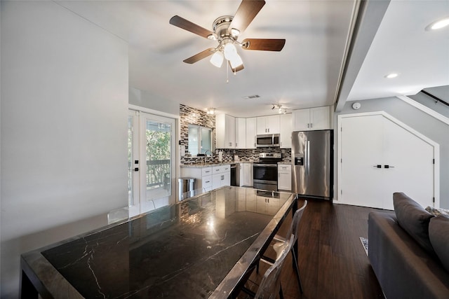 kitchen featuring ceiling fan, appliances with stainless steel finishes, backsplash, white cabinetry, and dark hardwood / wood-style floors