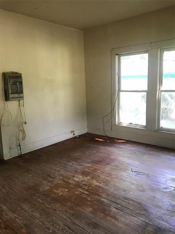 spare room featuring dark wood-type flooring and heating unit