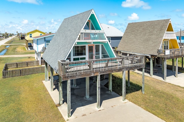 rear view of property with a wooden deck, a carport, and a lawn