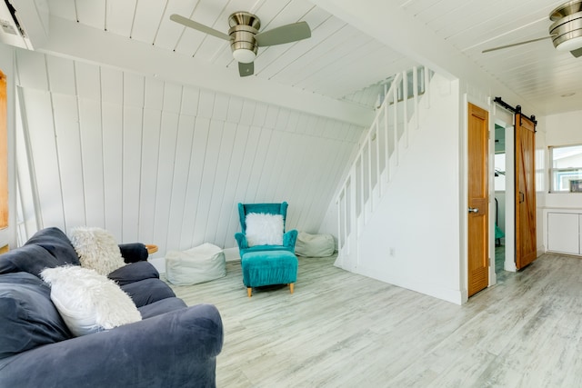 living room with ceiling fan, a barn door, hardwood / wood-style flooring, and an AC wall unit