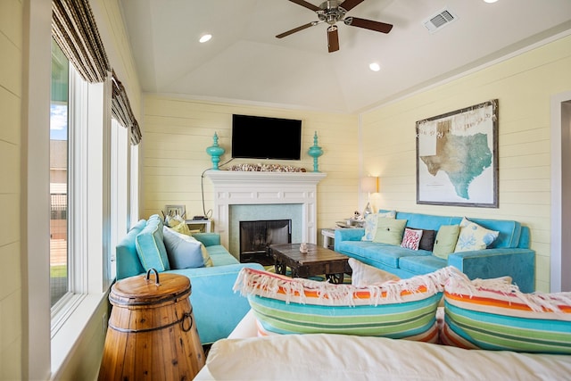 living room with ceiling fan, lofted ceiling, and wooden walls