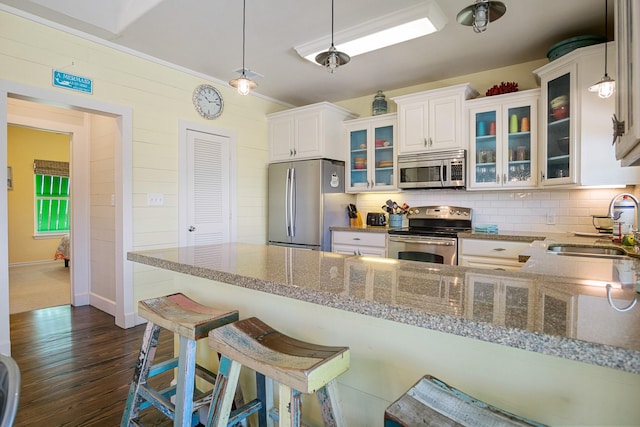 kitchen featuring white cabinets, sink, hanging light fixtures, light stone countertops, and appliances with stainless steel finishes