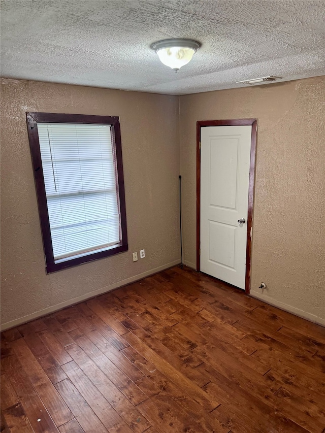 spare room with a textured ceiling and dark hardwood / wood-style floors