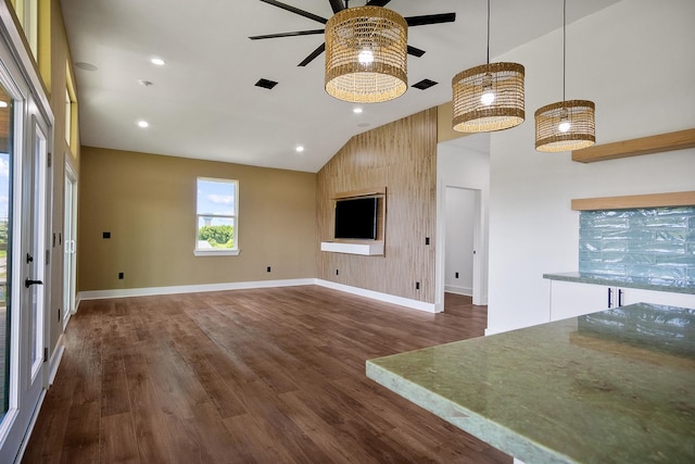 unfurnished living room featuring high vaulted ceiling, dark hardwood / wood-style floors, ceiling fan, and wood walls