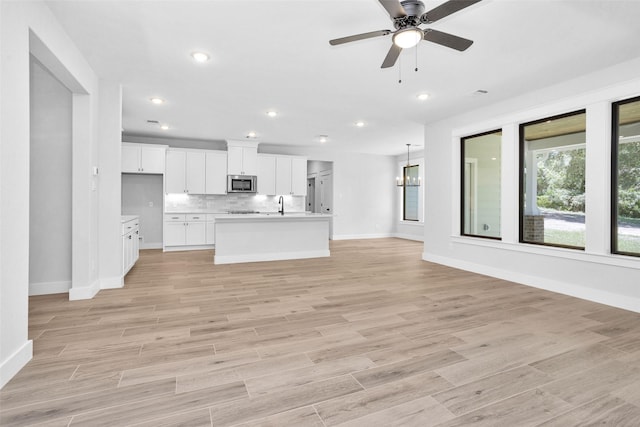 651 Paradise Dr, Coldspring, TX 77331 - unfurnished living room featuring baseboards, ceiling fan, a sink, light wood finished floors, and recessed lighting