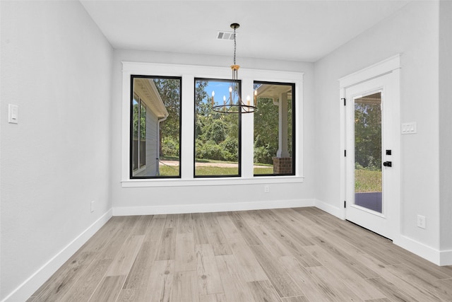 unfurnished dining area featuring light hardwood / wood-style flooring and a chandelier